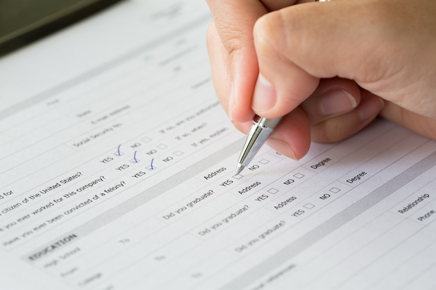 Hand mit stift über leere kontrollkästchen im antragsformular