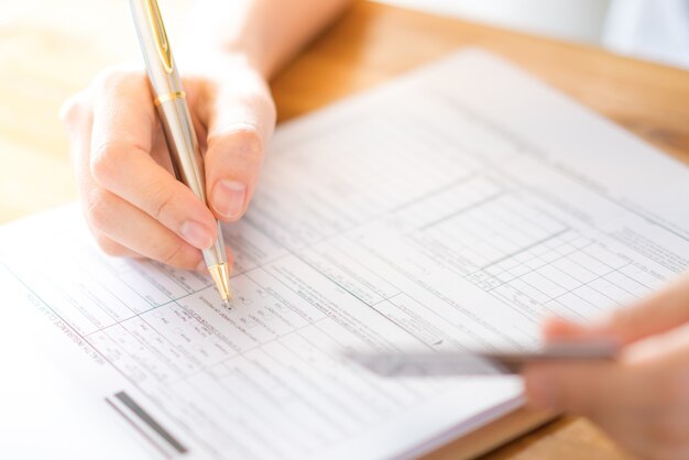 Hand mit Stift und Kreditkarte über Antragsformular.