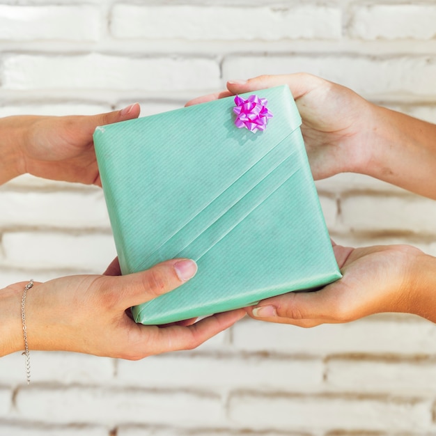 Kostenloses Foto hand mit zwei freundinnen, die grüne geschenkbox hält