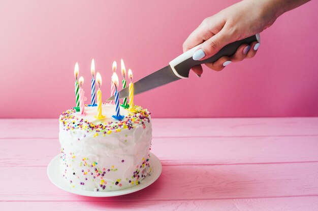 Hand schneiden Kuchen mit Kerzen