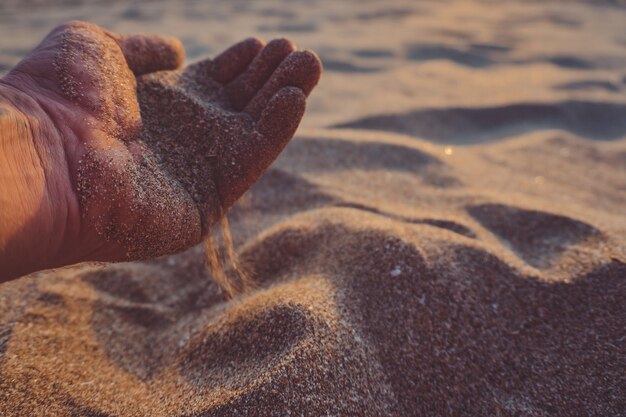 Hand schüttet Sand aus.