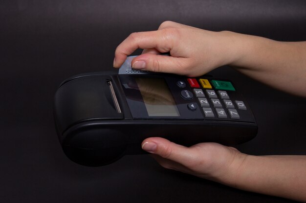 Hand Swiping Kreditkarte im Speicher. Weibliche Hände mit Kreditkarte und Bank-Terminal. Farbe Bild von einem POS und Kreditkarten.
