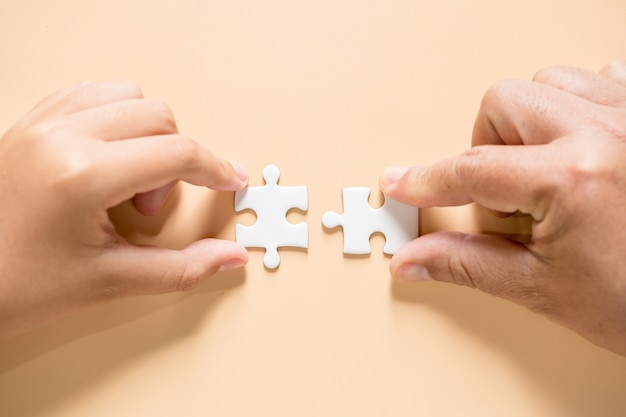 Hand verbinden Puzzleteile auf dem Tisch