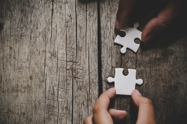 Hand verbinden Puzzleteile auf dem Tisch