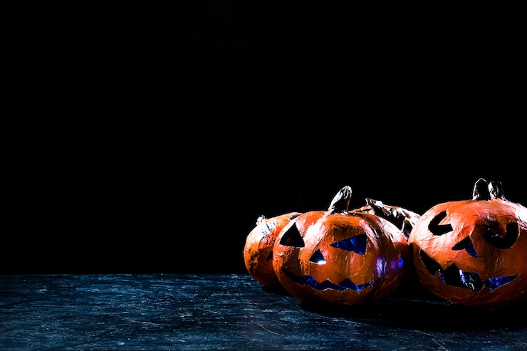 Kostenlose Foto handgemachte kürbise in der halloween-art belichteten das innere, das auf seite in der dunkelheit liegt