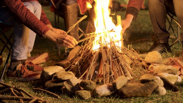 Handheld-Aufnahmen von einem Mann, der in einer kalten Nacht Lagerfeuer für seine Freunde macht.