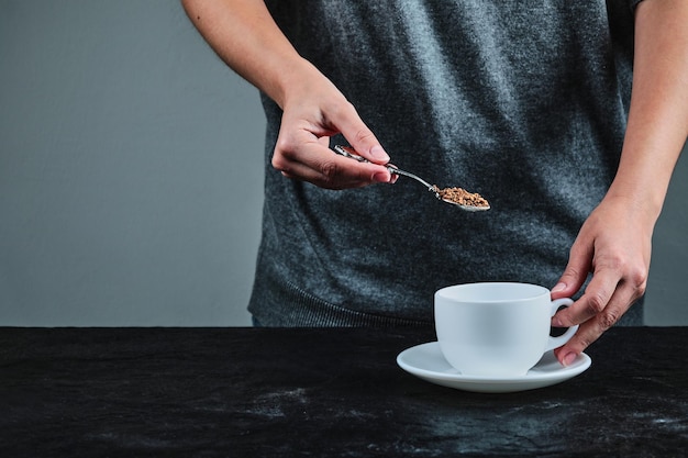 Handholdong-löffel voll kaffee auf schwarzem.