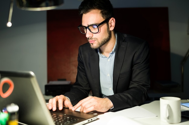 Handsome junge Geschäftsmann arbeitet mit Laptop im Büro.