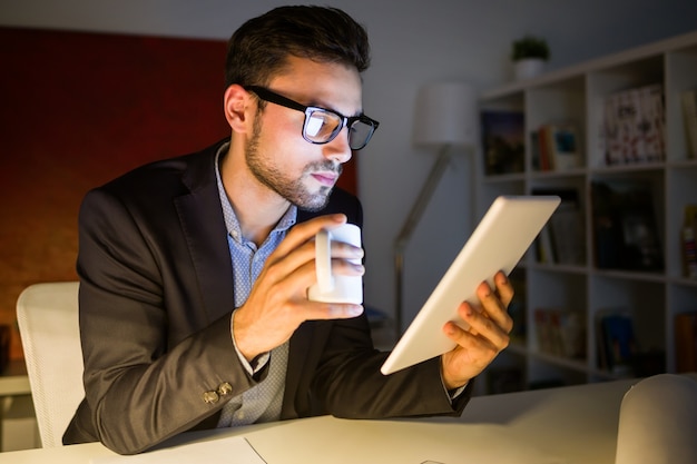 Handsome junge mann arbeitet mit digitalen tablette im büro.