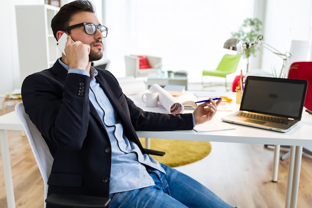 Handsome junge Mann mit seinem Handy im Büro.