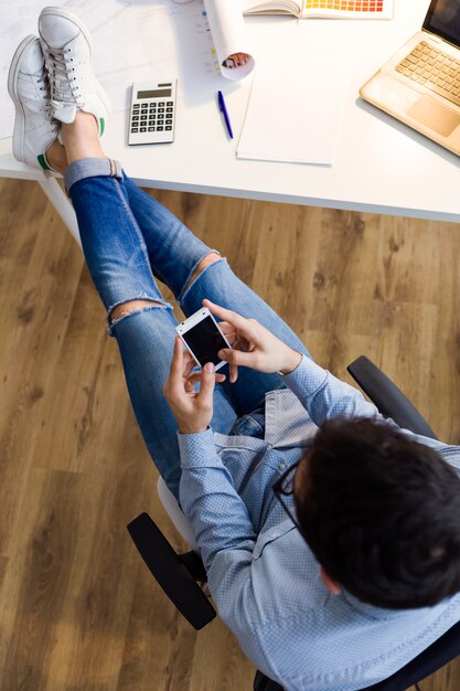 Handsome junge Mann mit seinem Handy im Büro.