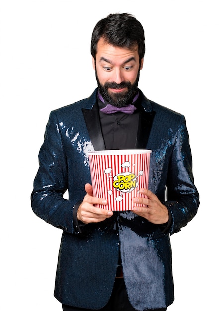 Handsome Mann mit Paillettenjacke essen Popcorns