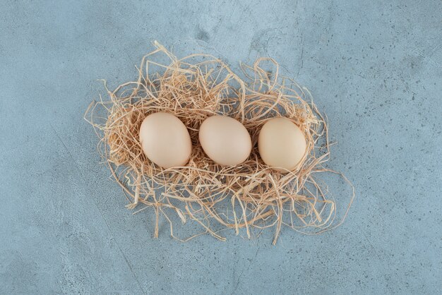Handvoll Eier auf einem kleinen Haufen Stroh auf Marmorhintergrund. Hochwertiges Foto