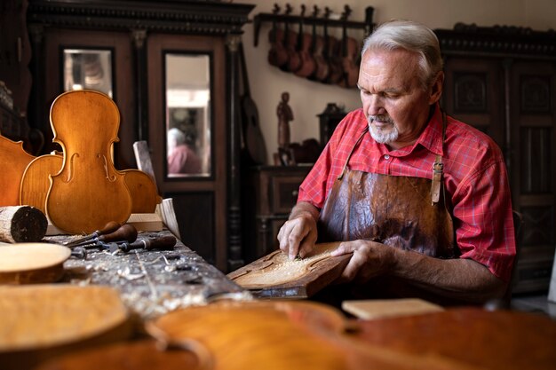 Handwerker, der Holz schnitzt, um Geigenmusikinstrument zu schaffen