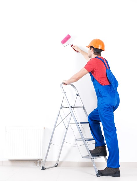 Handwerker Maler steht auf der Treppe mit Walze, volles Porträt auf Weiß