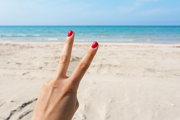 Handzeichen über blauem Meer- und Himmelhintergrundsommerreiseferienferienkonzepthintergrund