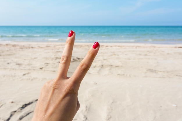 Handzeichen über blauem Meer- und Himmelhintergrundsommerreiseferienferienkonzepthintergrund