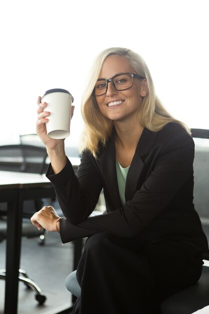 Happy Geschäftsfrau sitzt mit Kaffee im Büro