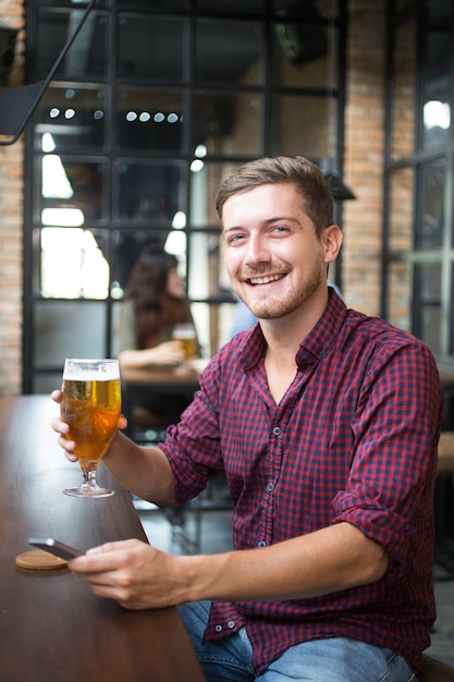 Happy Man Holding Smartphone und Glas Bier