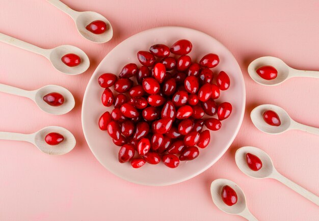 Hartriegelbeeren in Teller und Holzlöffel auf rosa.