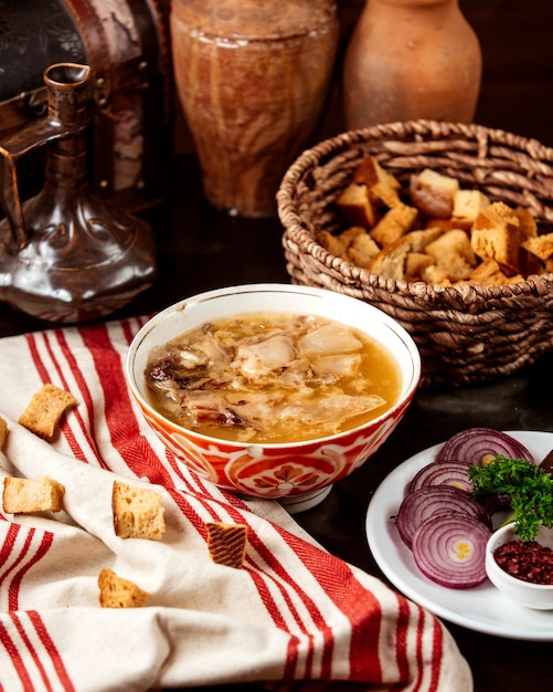 Haschisch traditionelles aserbaidschanisches Gericht der Seitenansicht in einem Kyasa-Teller mit Zwiebeln und Crackern