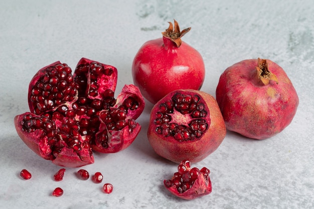 Haufen Granatäpfel. Geschnittener oder ganzer Granatapfel auf grauer Oberfläche.