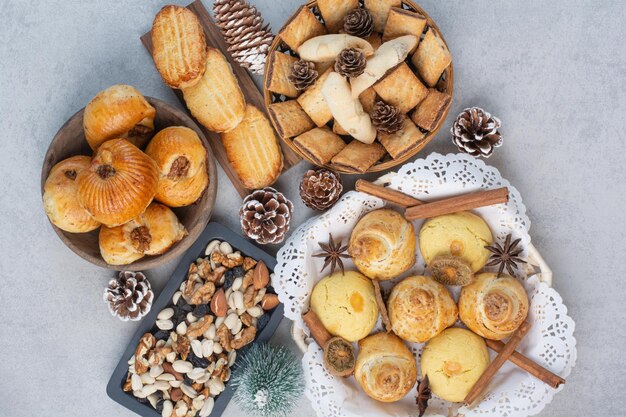 Haufen verschiedener Kekse, Nüsse und Tannenzapfen in Schalen. Foto in hoher Qualität
