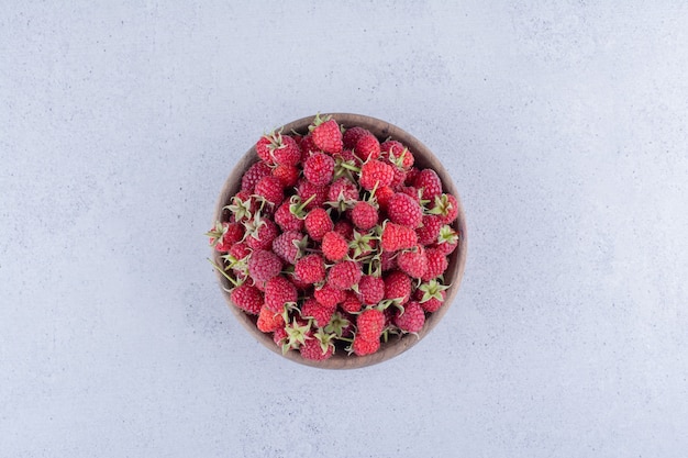 Haufen von Beeren in einer hölzernen Schüssel auf Marmorhintergrund.