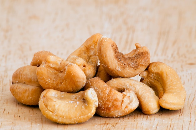 Haufen von gerösteten Cashewnüssen auf einem alten Holztisch.