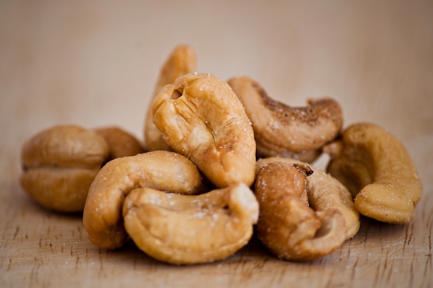 Haufen von gerösteten Cashewnüssen auf einem alten Holztisch.