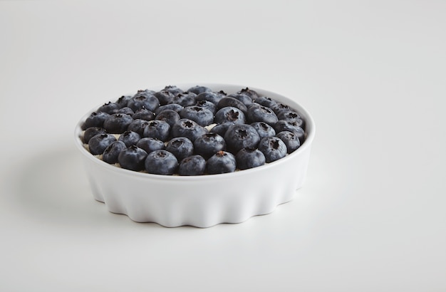 Haufen von Heidelbeer-Antioxidans-Bio-Superfood im Keramikschalenkonzept für gesunde Ernährung und Ernährung lokalisiert auf weißem Tisch