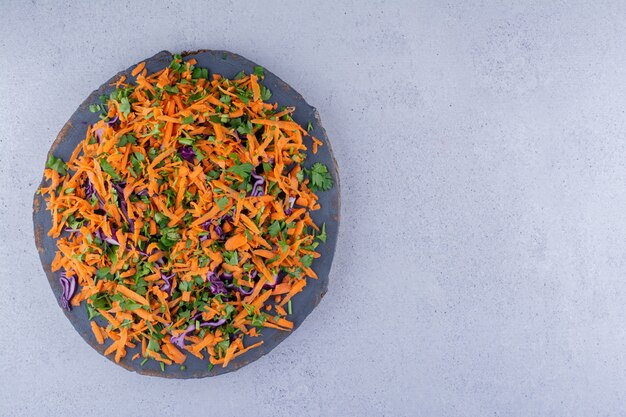 Haufen von Karotten und Rotkohl gehackt in einen Salat auf einem Brett auf Marmorhintergrund. Foto in hoher Qualität