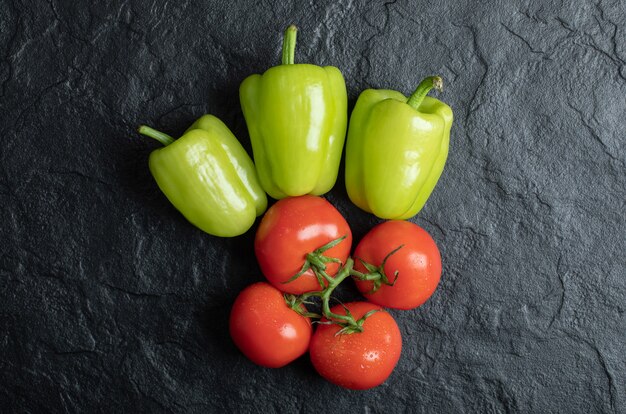 Haufen von Tomaten und Pfeffer auf schwarzem Hintergrund