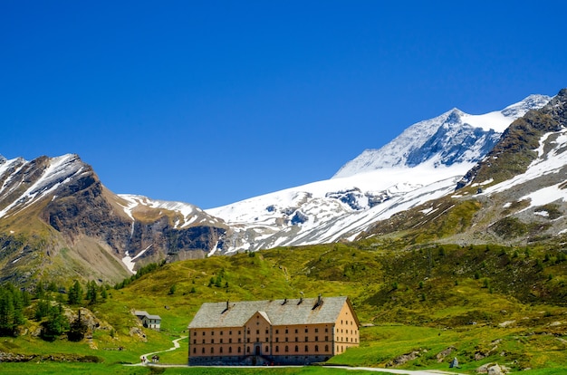 Kostenloses Foto haus umgeben von felsigen bergen bedeckt mit grün und schnee im wallis in der schweiz