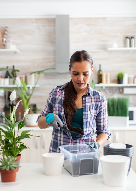 Hausfrau arbeitet zu Hause in der Küche mit Handschuhen und Schaufel