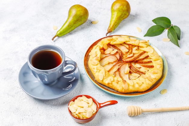 Hausgemachte birnen-galette-torte mit mandelblättern und frischen reifen grünen birnen