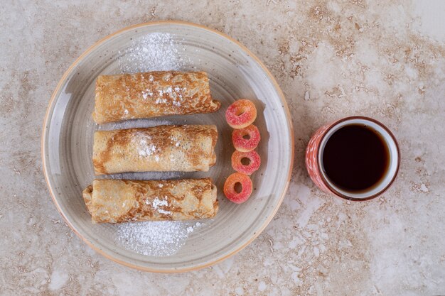 Hausgemachte Crepes mit Zuckerpulver und einer Tasse Tee