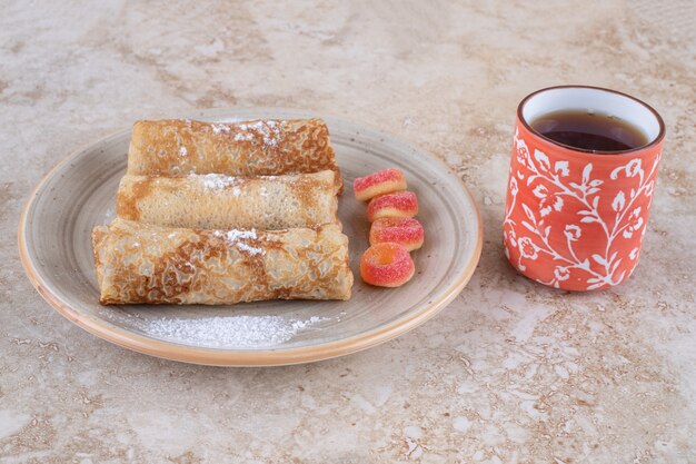 Hausgemachte Crepes mit Zuckerpulver und einer Tasse Tee