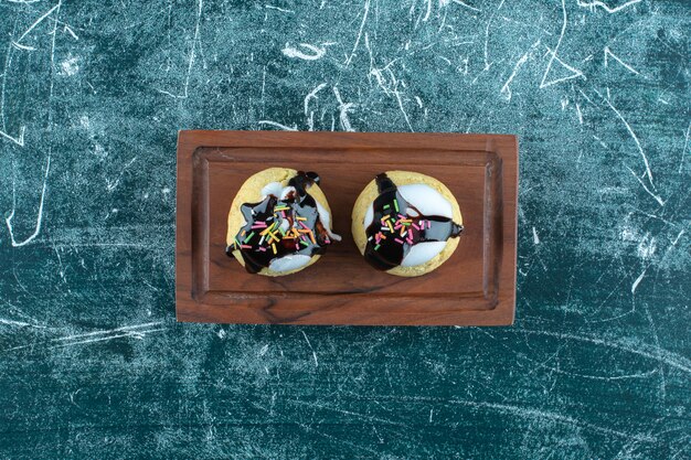 Hausgemachte glasierte Kekse auf einer Holzplatte, auf blauem Hintergrund. Foto in hoher Qualität