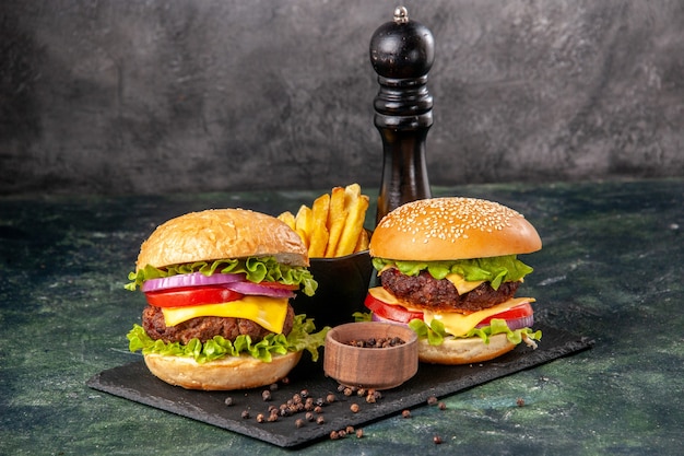 Hausgemachte leckere Sandwiches auf schwarzem Schneidebrett Pommes Ketchup auf dunkelgrauer verschwommener Oberfläche