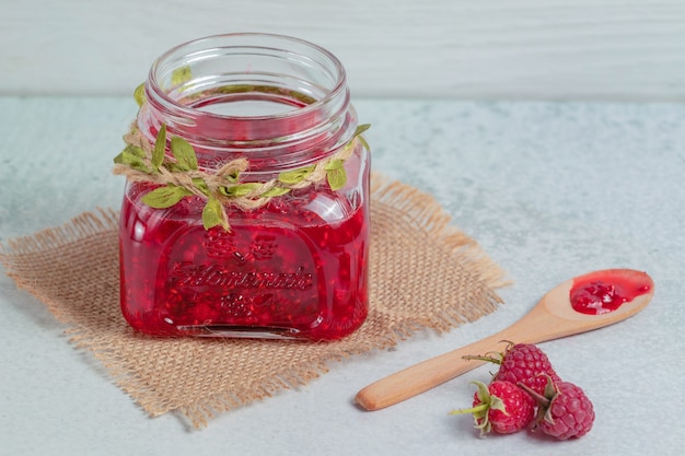 Hausgemachte marmelade und frische himbeeren auf grauer oberfläche.