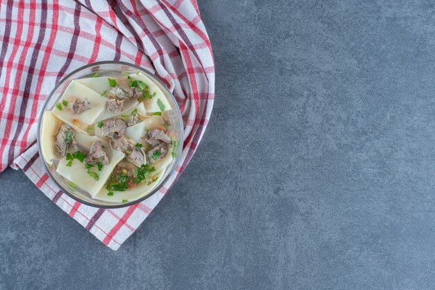 Hausgemachte Suppe mit Trockenfleisch und Teig in Glasschüssel.