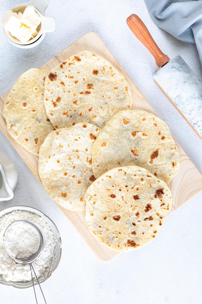 Hausgemachte Weizentortillas Fladenbrot Tortilla Pita mit Zutaten zum Kochen auf einem weißen Tisch Draufsicht Vertikal