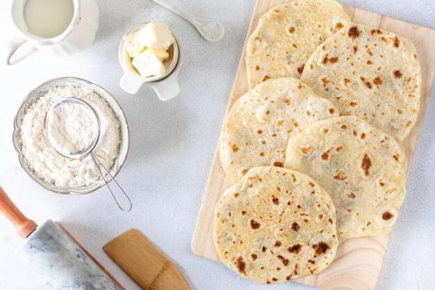 Hausgemachte Weizentortillas Fladenbrot Tortilla Pita mit Zutaten zum Kochen auf einem weißen Tisch Draufsicht