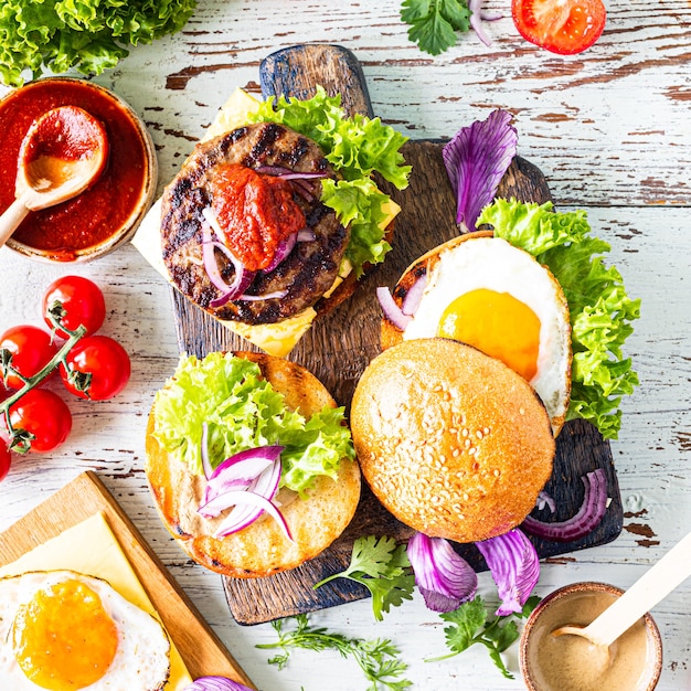 Hausgemachten Burger machen. Zutaten zum Kochen auf einem Holztisch. Ansicht von oben.