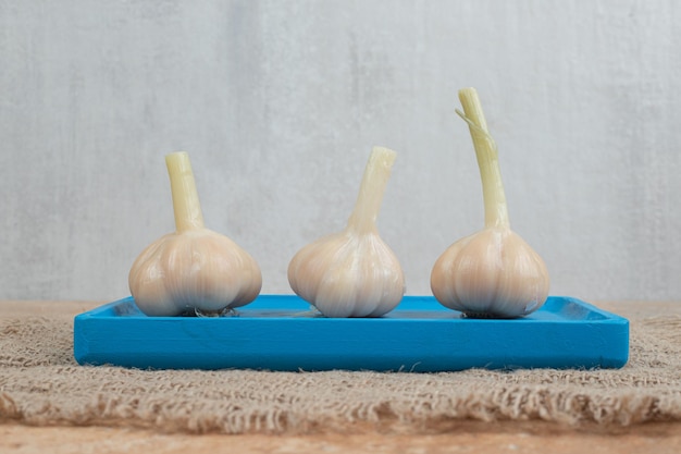 Hausgemachter fermentierter Knoblauch auf blauem Teller mit Sackleinen