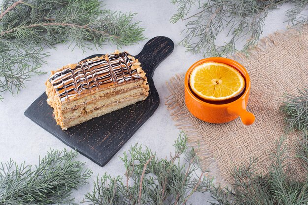 Hausgemachter Kuchen und eine Tasse Tee auf Marmoroberfläche mit Tannenzweig. Foto in hoher Qualität