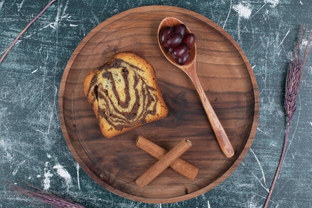 Hausgemachter Zebrakuchen auf Holzplatte mit Zimt und Trauben.