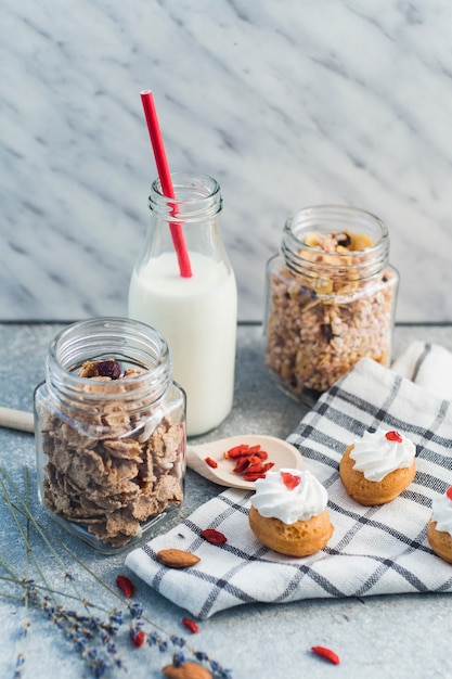 Kostenloses Foto hausgemachtes granola; müsli; muffins kuchen; trockenfrüchte; milch mit rotem stroh und tuch auf konkretem hintergrund