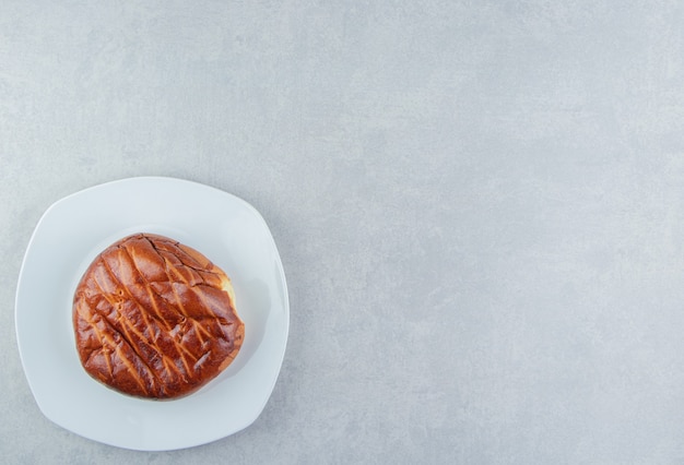 Hausgemachtes süßes Brötchen auf weißem Teller.